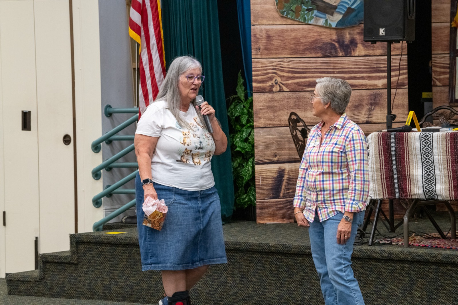 Two women in conversation, one holding a microphone, at a LightHouse PBC community gathering