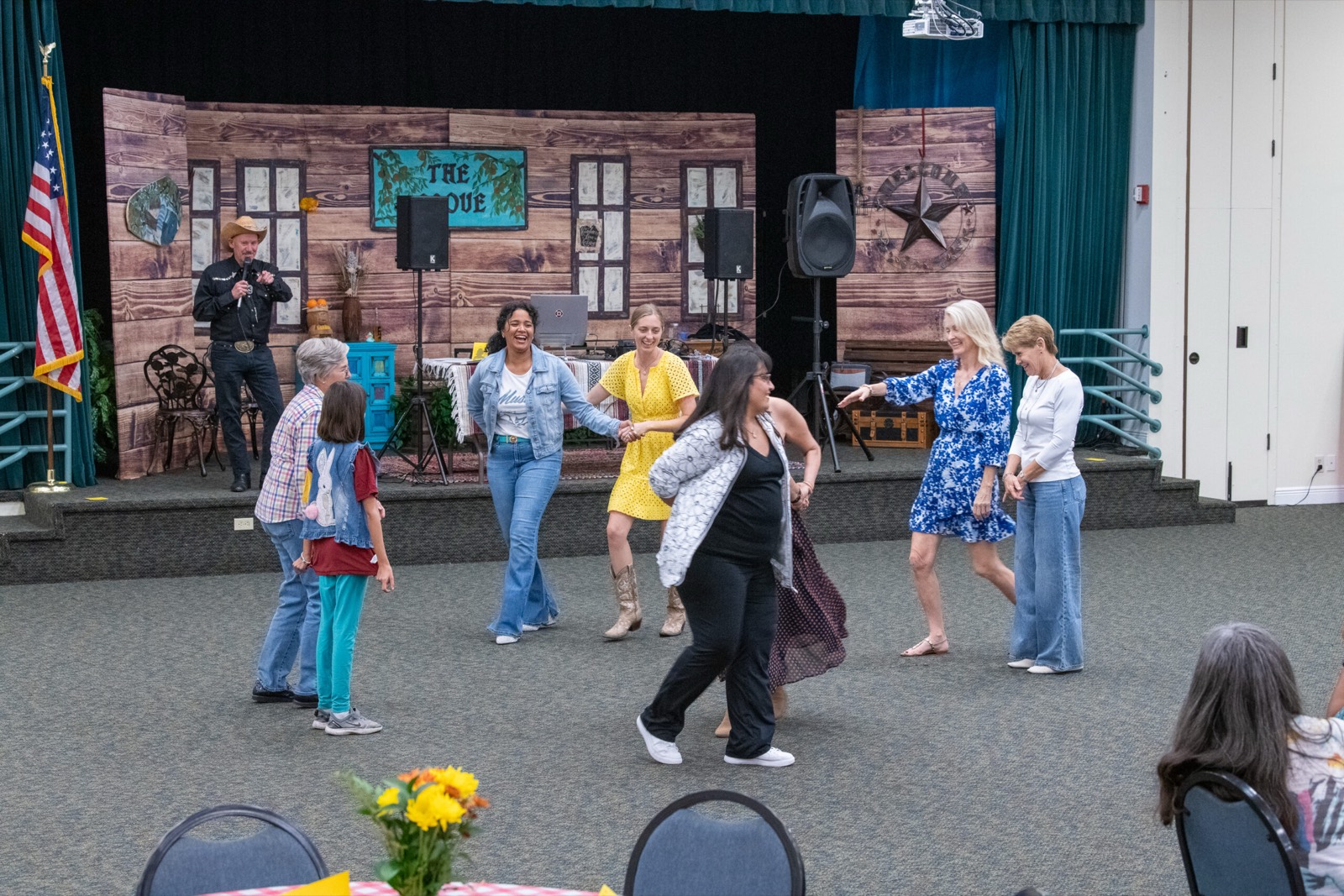 Guests dancing in a line on the floor while a band plays on the barn stage