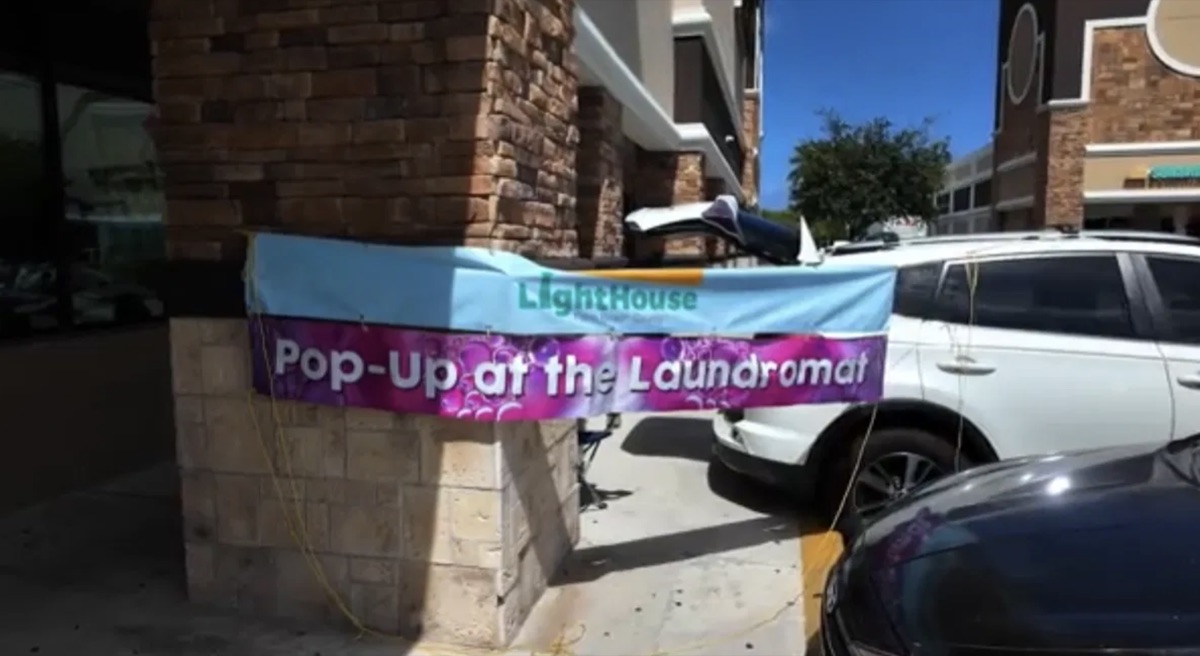 A LightHouse PBC Pop-Up at the Laundromat banner hung outside a laundromat storefront